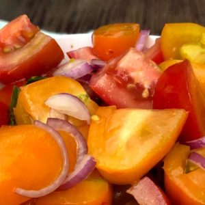 Image contains a photo of a bowl of chopped tomatoes with red onion, basil, chili flakes, oil, and vinegar.